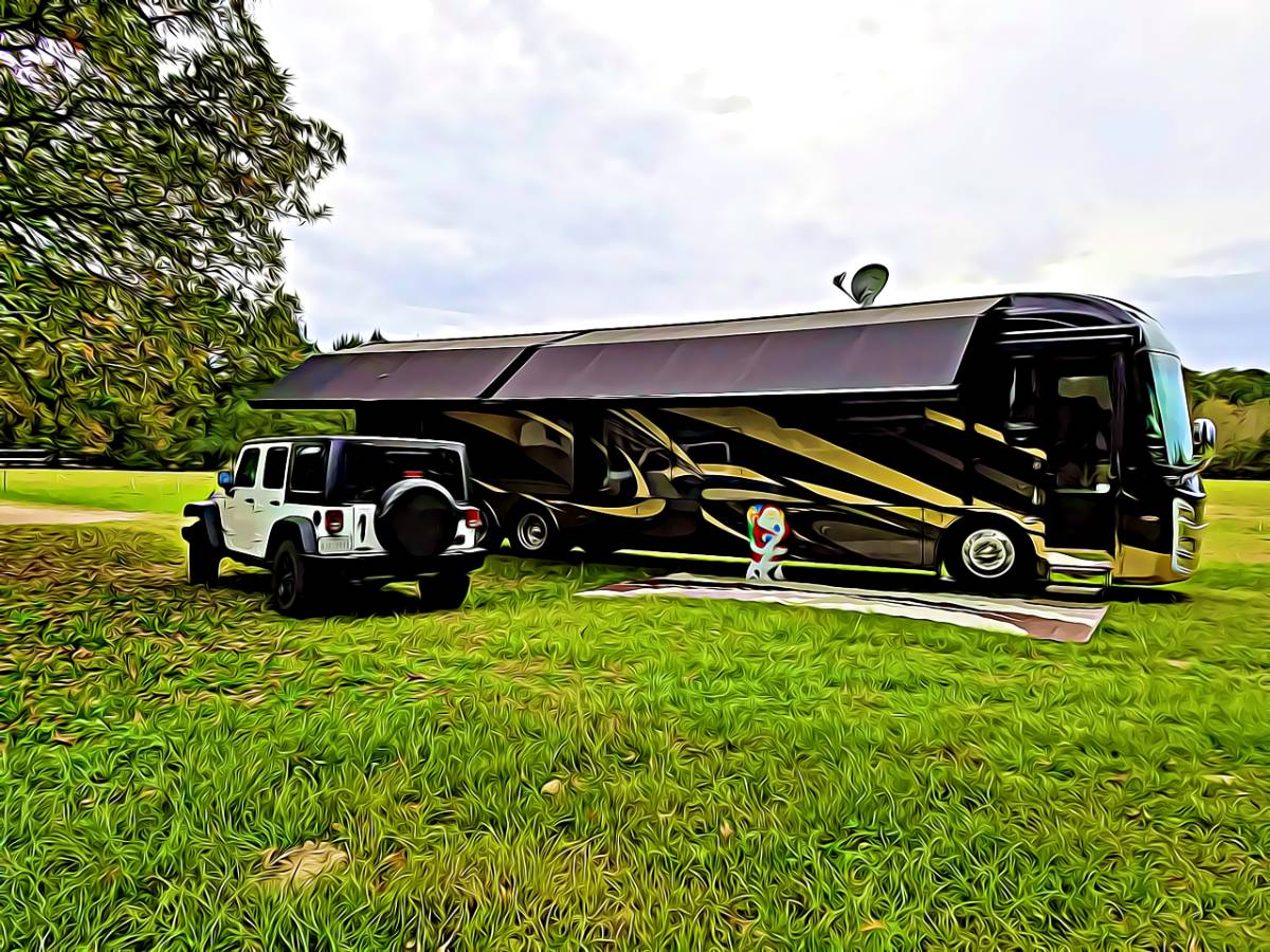 Class A motorhome parked and set up with awning out and towed vehicle in campground that is big rig friendly