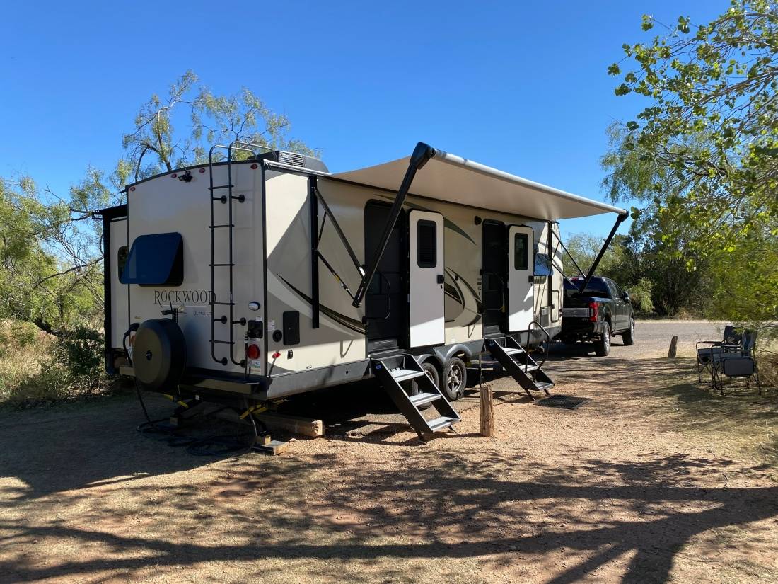 Travel trailer and truck setup in RV site with doors open and awning out at Caprock Canyons State Park