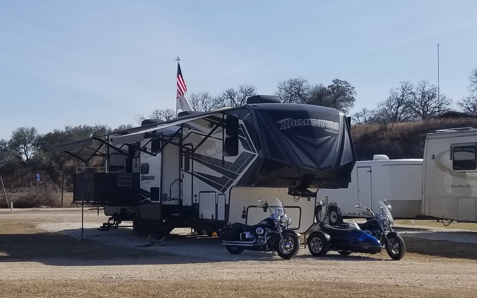 An RV with two motorcycles in an RV park