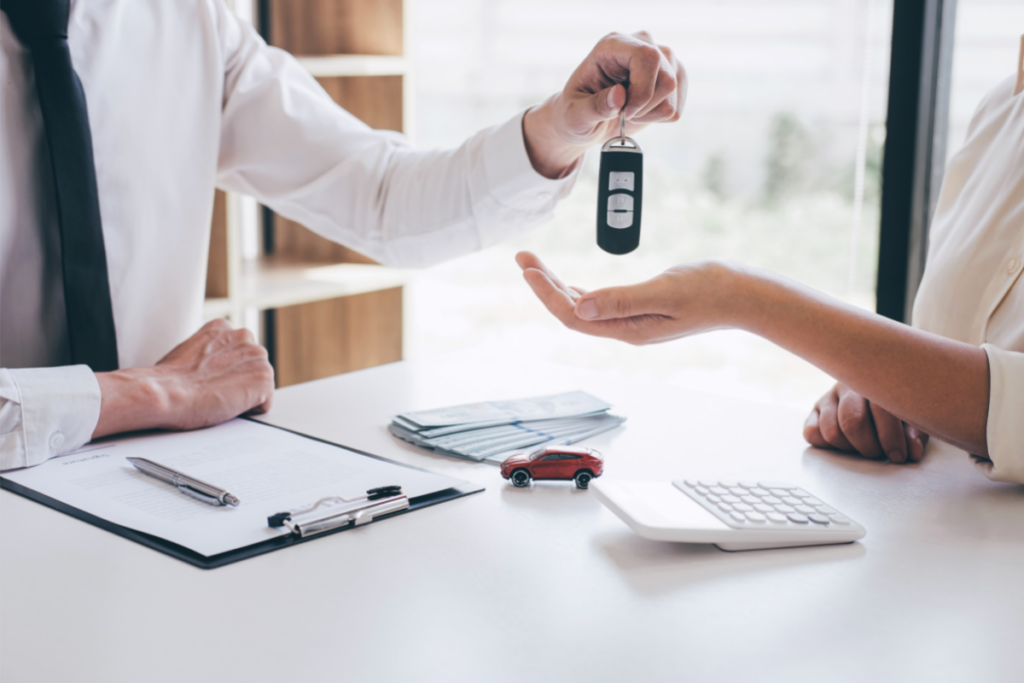 A dealer handing car keys to a purchaser - feature image for financing an RV as a primary residence