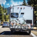Camper With 2 Bicycles on Back on Tree-lined Highway