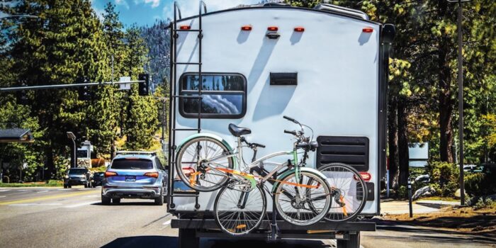 Camper With 2 Bicycles on Back on Tree-lined Highway