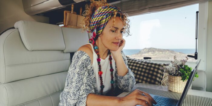 Woman with laptop works remotely form inside an RV