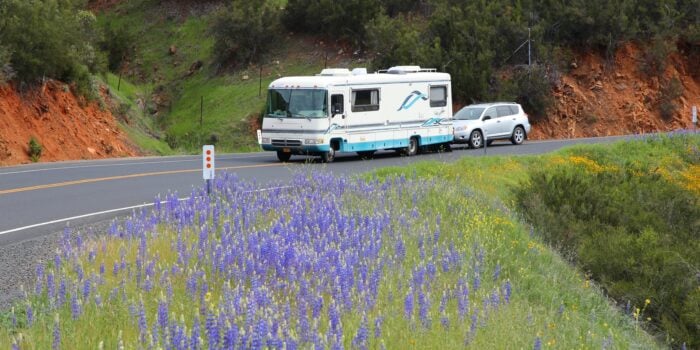 RV towing car in front of field of flowers - feature image for rv mistakes