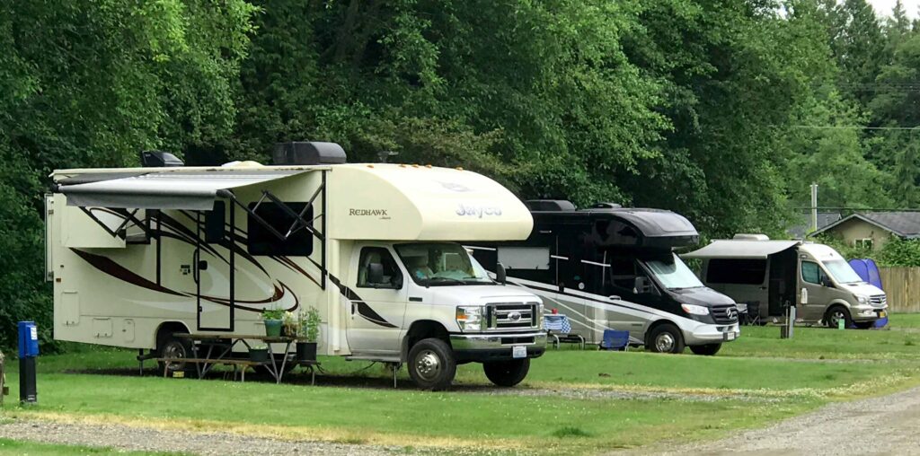 A class C class B+ and a class B RV all lined up in a campground