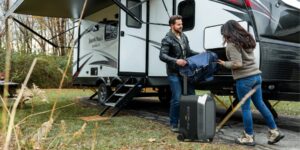 man and woman load a travel trailer with equipment