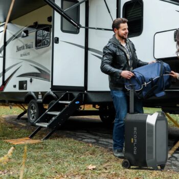 man and woman load a travel trailer with equipment