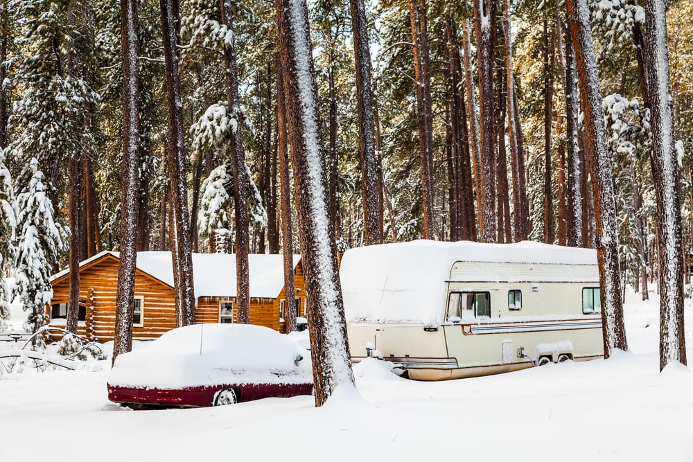 Log cabin with rv and car covered in snow