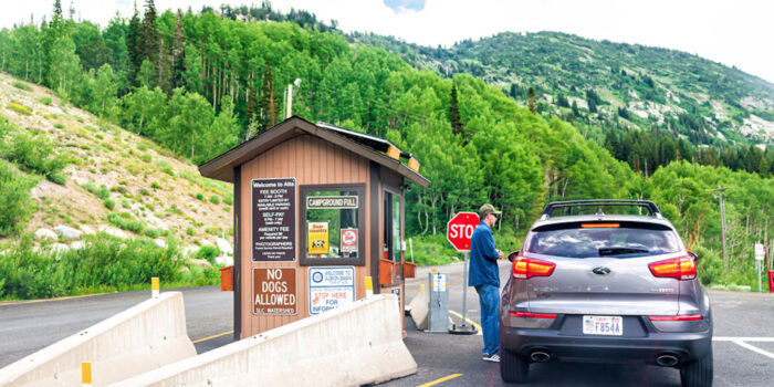 Park ranger approaches car at park entrance with information sign
