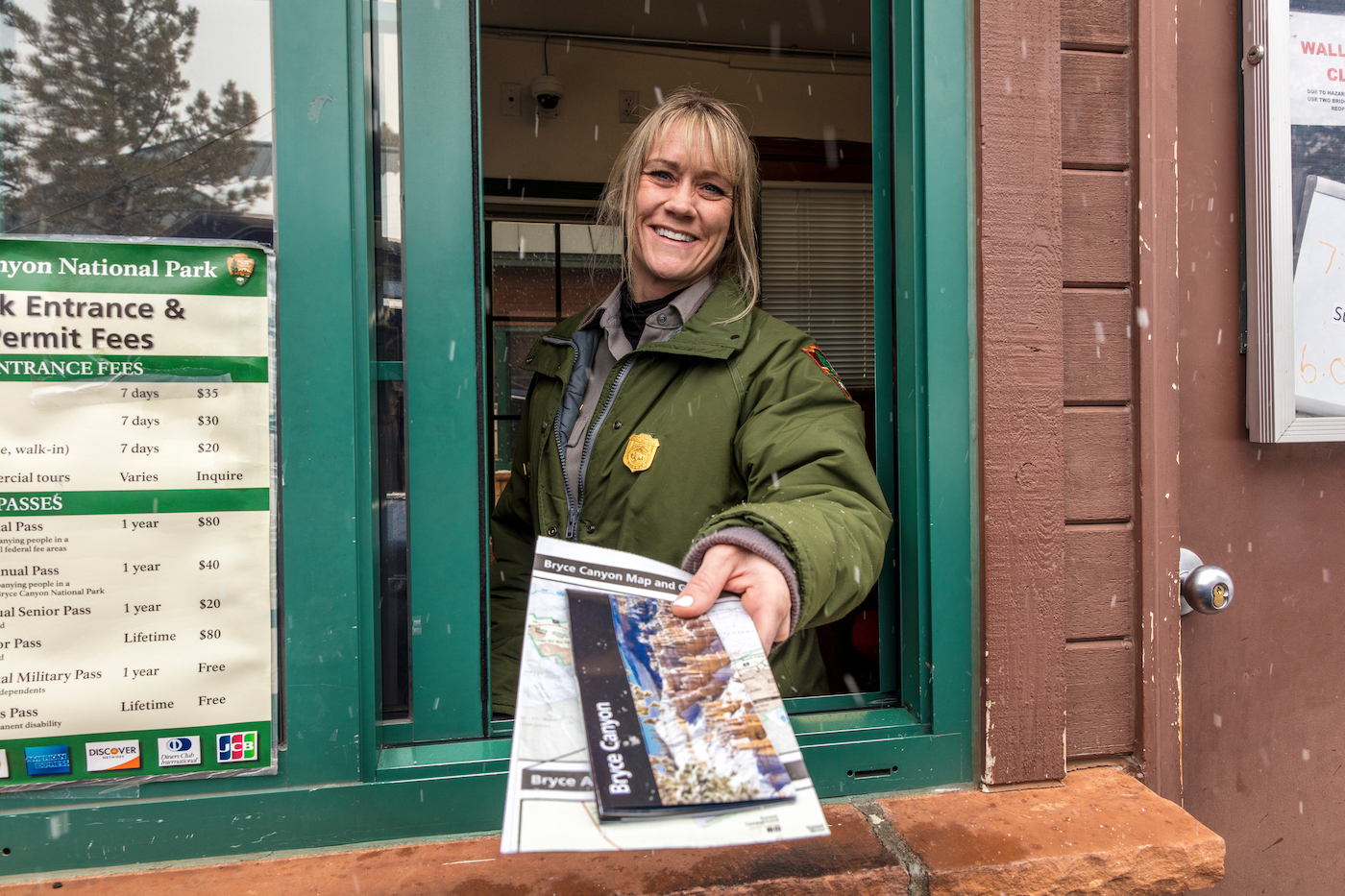 Female blond National Park Ranger hands out brochure through window at Bryce National Park, Utah