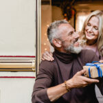 man and woman exchange rv gifts in the open door of their camper