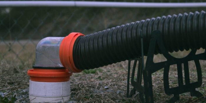 An RV sewer pipe fitting connected to dump station with 90 degree clear fitting