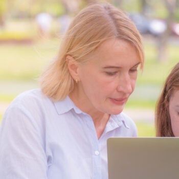 woman and girl looking at a laptop outside