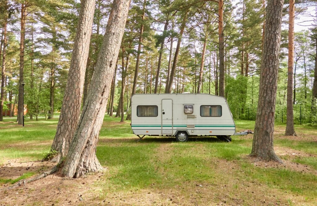 RV trailer in campsite, feature image for full-time RV living monthly costs