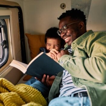 father reading to son in a camper