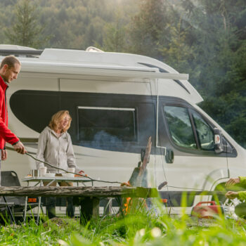 Class B motorhome with three adults cooking outside