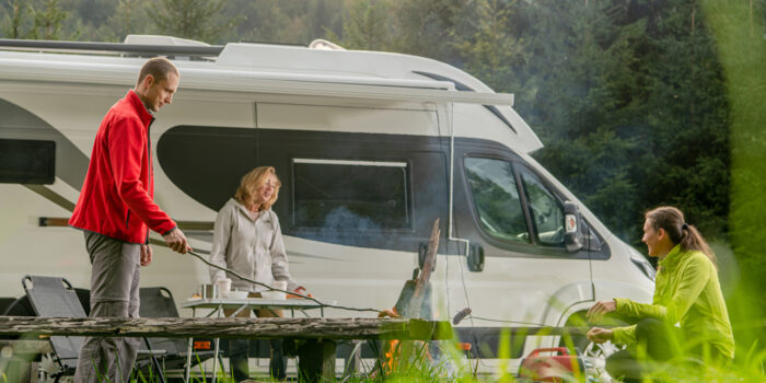 Class B motorhome with three adults cooking outside