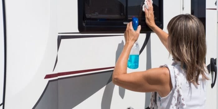 A woman cleaning the windows on a motorhome.
