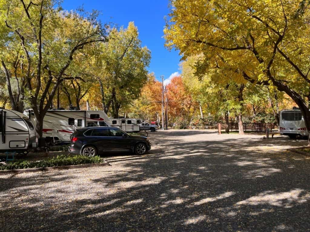 A wooded top-rated RV campground, Rancho Sedona RV Park, with RVs and tow vehicles in the foreground.