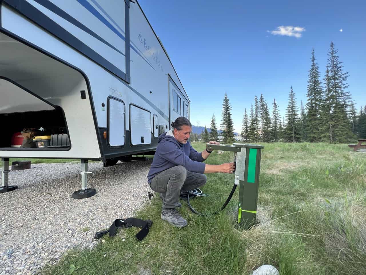A man plugging his fifth-wheel into the campground pedestal.