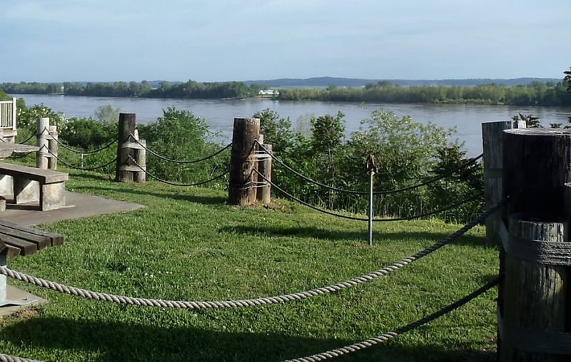 green grass in foreground with stone pillars overlooking a river