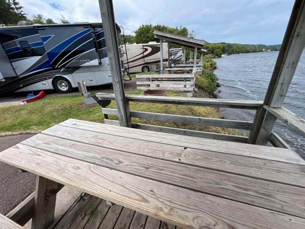 A view over a picnic table showing a waterfront site and neighboring motorhomes at Houghton RV Park.