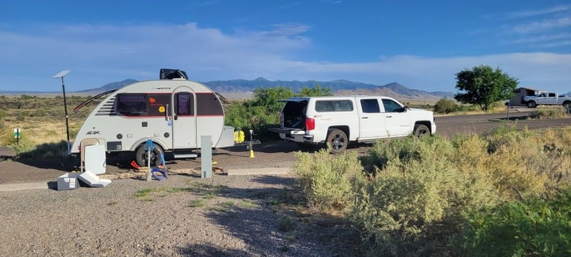 white pickup truck with topper pulling a teardrop camper at an affordable campground in New Mexico.