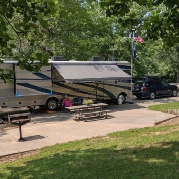 A motorhome and dinghy vehicle set up at a campground at Cave-in-Rock State Park affordable campground.