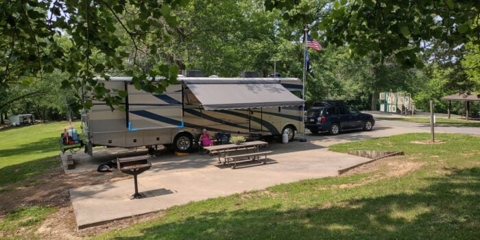 A motorhome and dinghy vehicle set up at a campground at Cave-in-Rock State Park affordable campground.