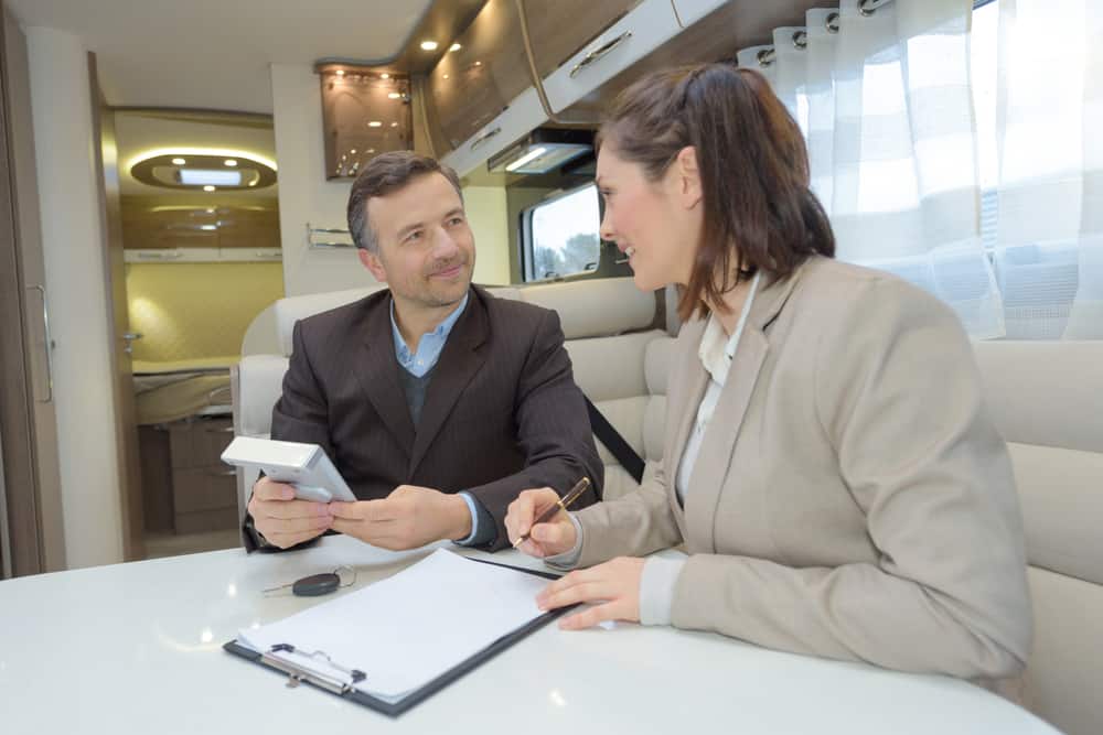 RV buyer inside a motorhome signs paperwork for an RV extended warranty.