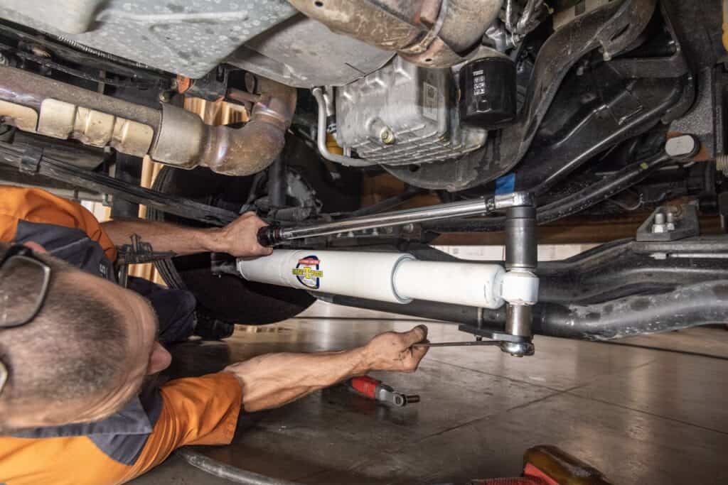 Am man installing a Safe-T-Plus steering stabilizer under a vehicle. Photo: Bruce W. Smith.