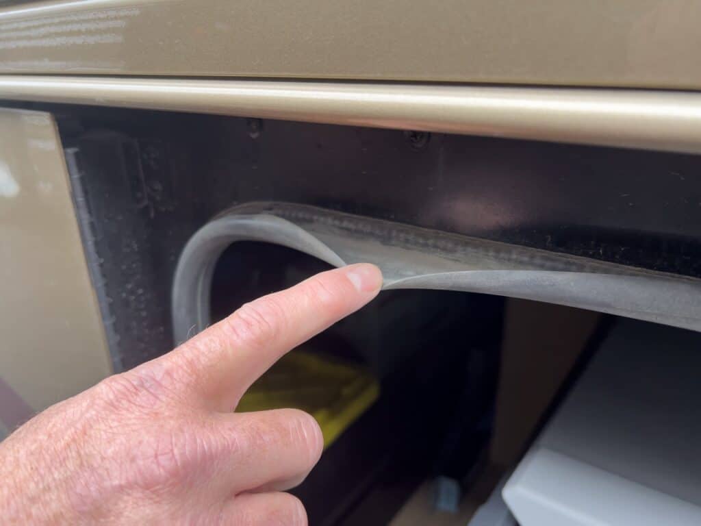 A man's finger pointing to the seal on an RV exterior compartment. Photo: Bruce W. Smith