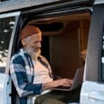 RV internet makes it possible for a bearded hipster man to work on his laptop while sitting inside his camper van