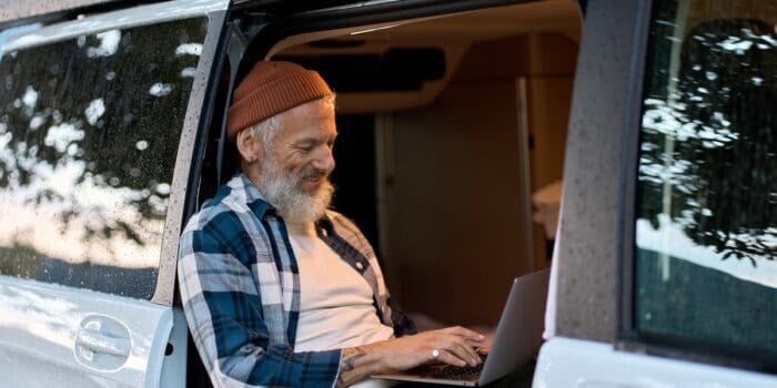 RV internet makes it possible for a bearded hipster man to work on his laptop while sitting inside his camper van