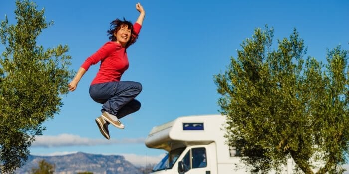 Woman able to find joy jumps in the air in front of her RV