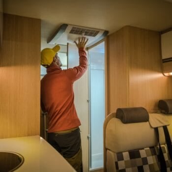 A man performing RV air conditioner maintenance inside his RV. Photo: Shutterstock.
