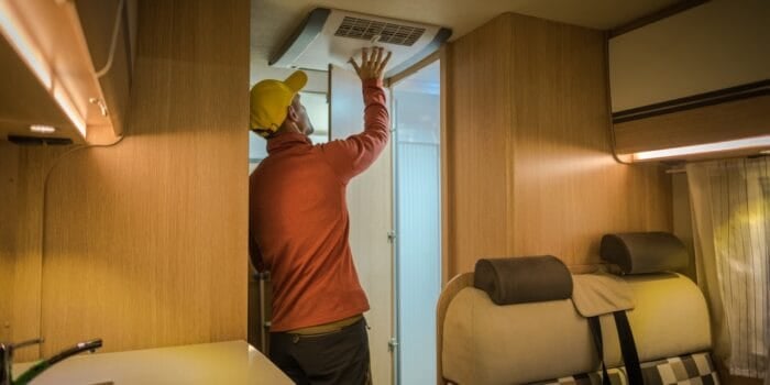 A man performing RV air conditioner maintenance inside his RV. Photo: Shutterstock.