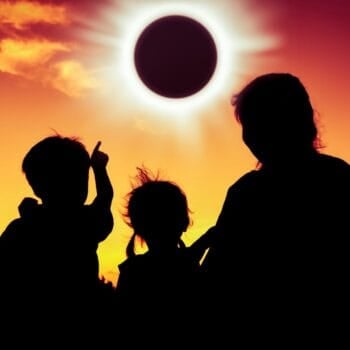 Silhouette from behind an RV family viewing a solar eclipse. Photo: Shutterstock.