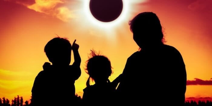 Silhouette from behind an RV family viewing a solar eclipse. Photo: Shutterstock.